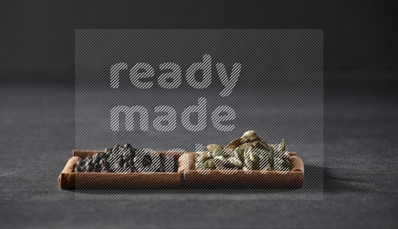 2 squares of cinnamon sticks full of black peppers and cardamom on black flooring