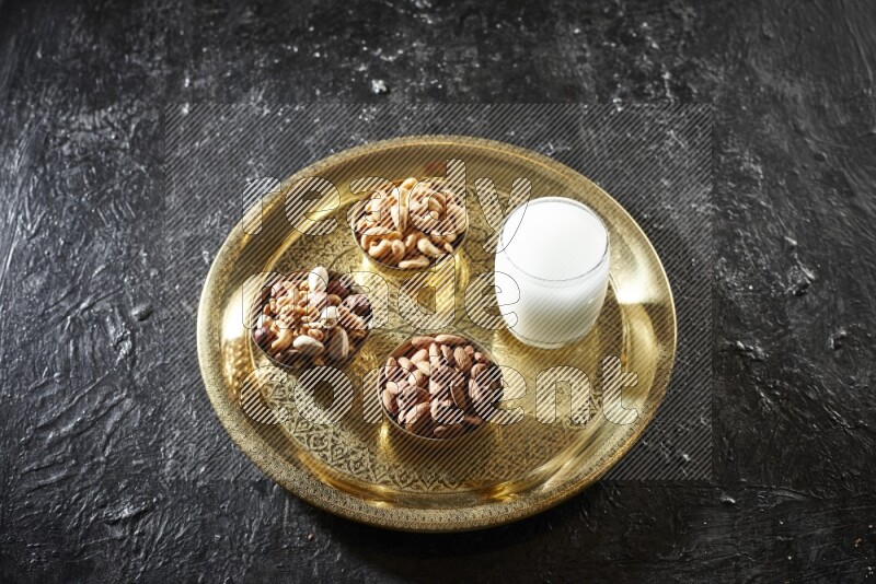 Nuts in metal bowls with sobya on a tray in dark setup