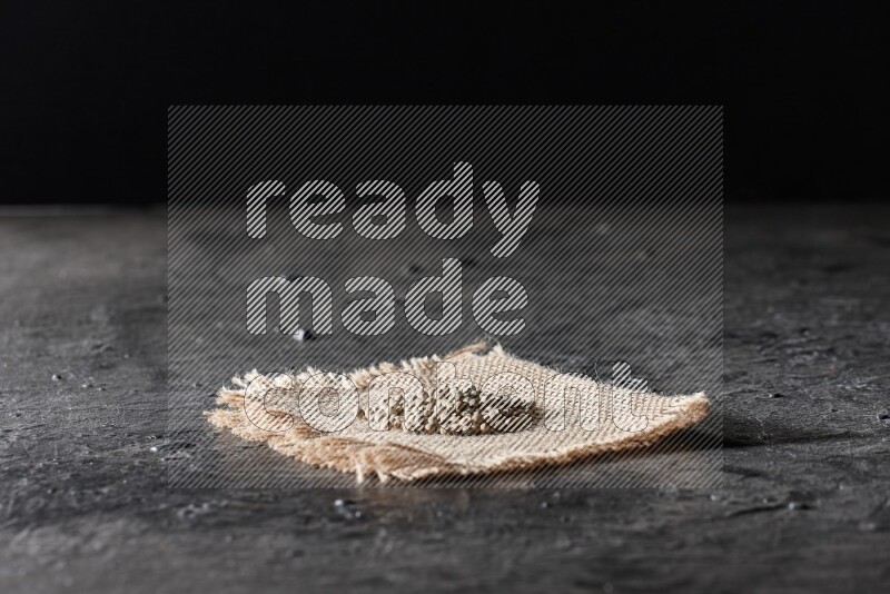 White pepper beads on a burlap piece of fabric on textured black flooring