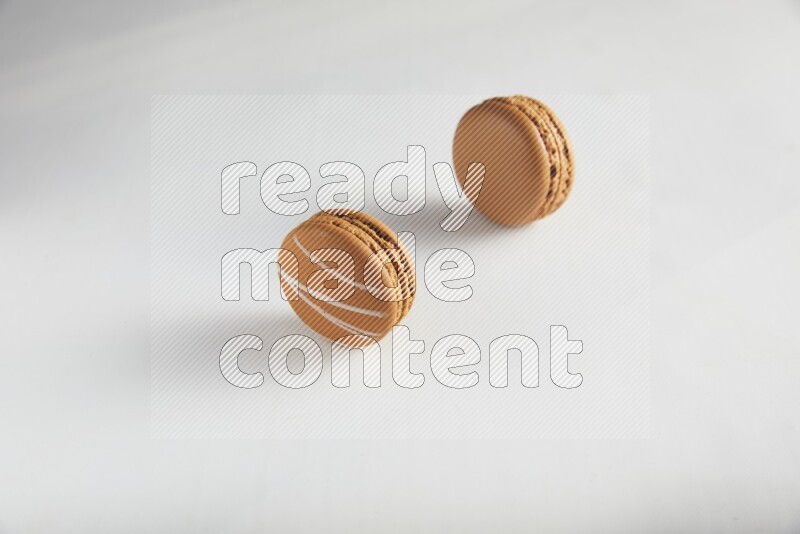 45º Shot of of two assorted Brown Irish Cream, and Brown Maple Taffy macarons  on white background