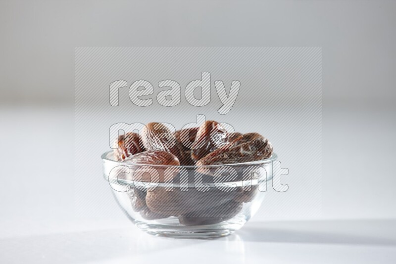 A glass bowl full of dried dates on a white background in different angles