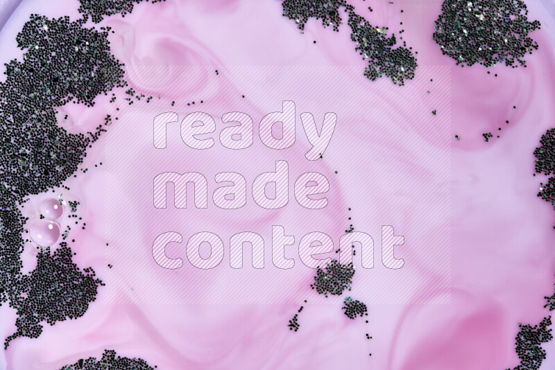 A close-up of sparkling green glitter scattered on swirling pink background