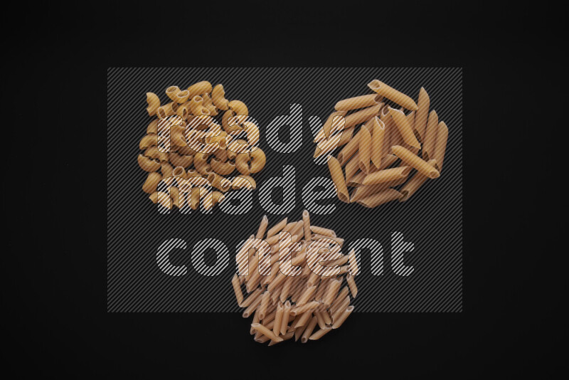 Different pasta types in bunches on black background