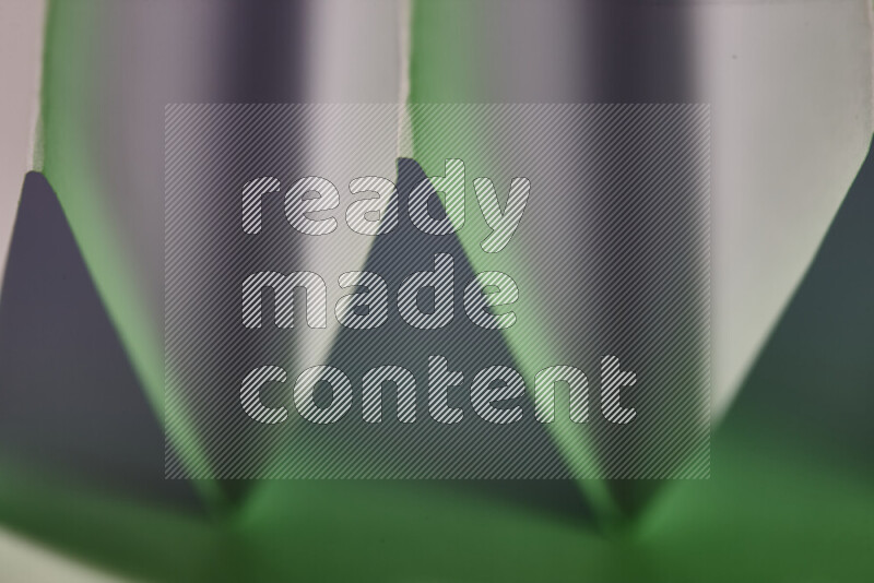 A close-up abstract image showing sharp geometric paper folds in white and green gradients