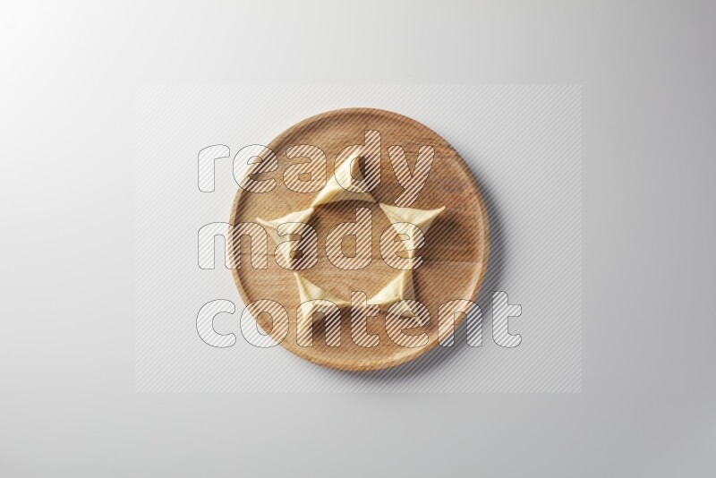 Five Sambosas on a wooden round plate on a white background
