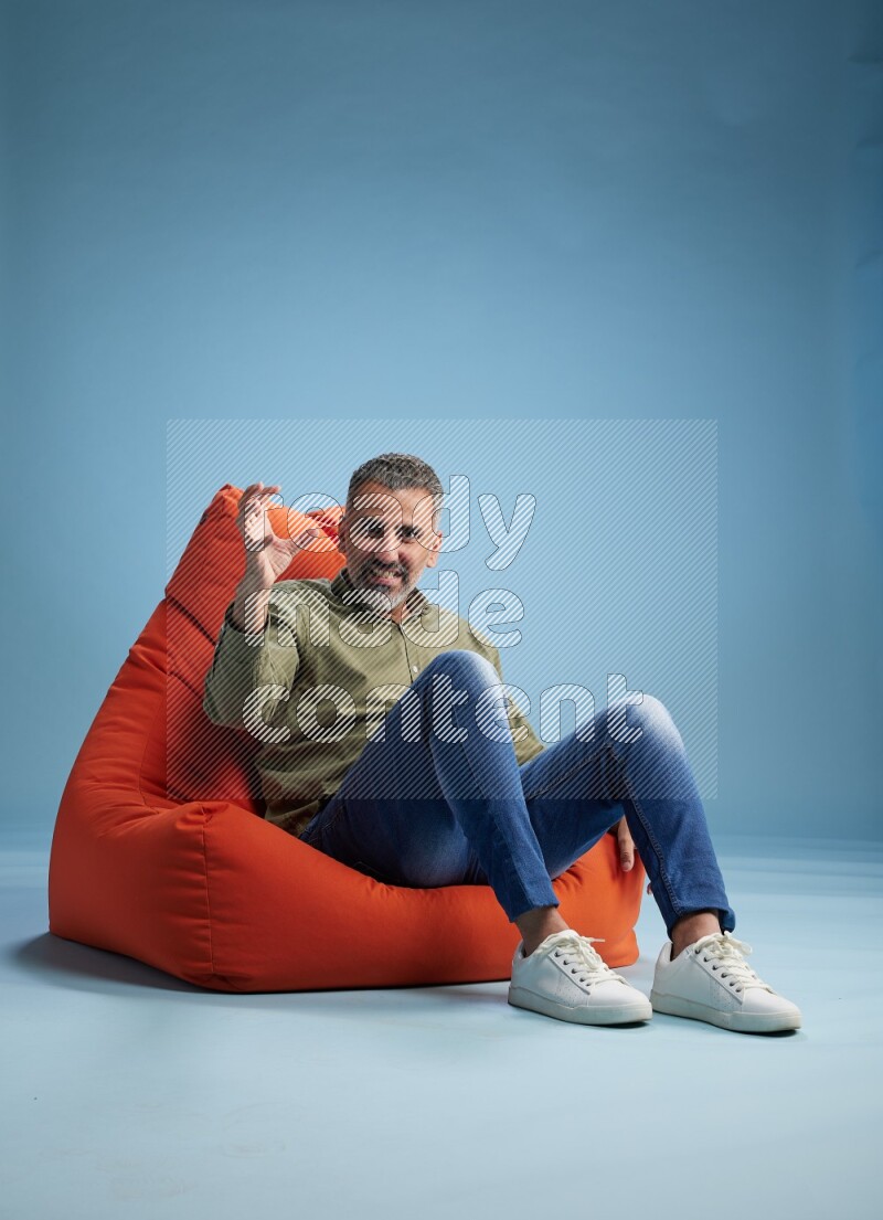 A man sitting on an orange beanbag and interacting with the camera