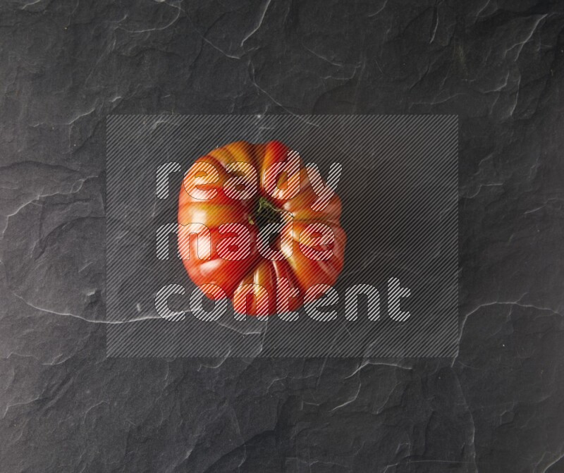 Single Topview Heirloom tomato on a black slate background