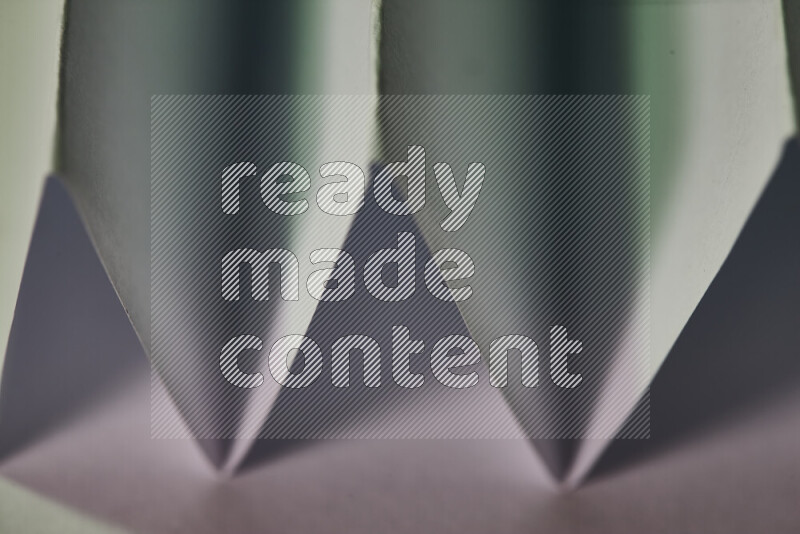 A close-up abstract image showing sharp geometric paper folds in white and green gradients