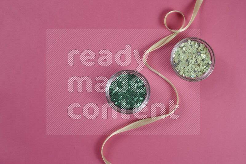 A green and pink collection of sewing and tailoring tools arranged on a pink background
