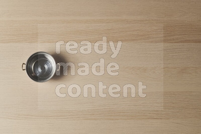 A small copper pot on light wooden background