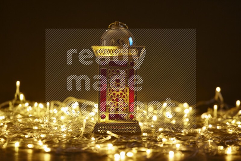 A traditional ramadan lantern surrounded by glowing fairy lights in a dark setup