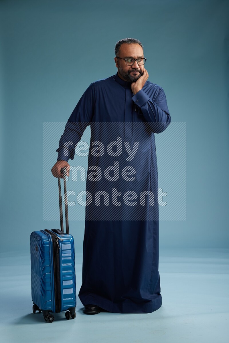 Saudi Man without shimag Standing pulling travel bag on blue background