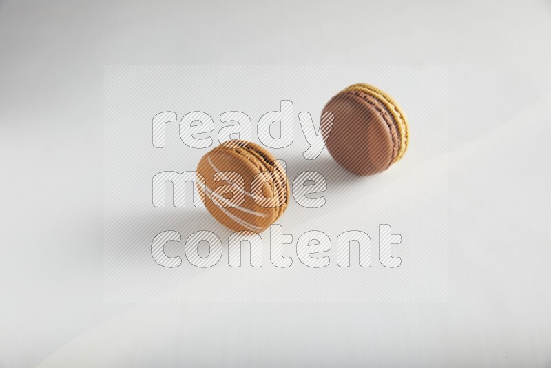 45º Shot of of two assorted Brown Irish Cream, and Yellow, and Brown Chai Latte macarons on white background