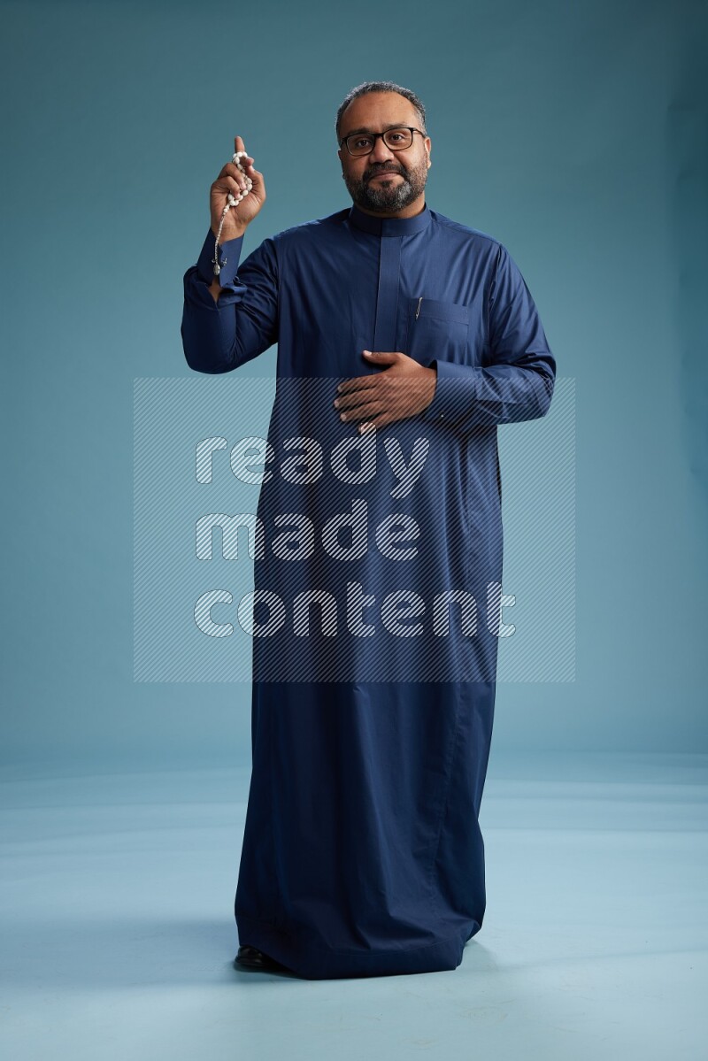 Saudi Man without shimag Standing Interacting with the camera on blue background