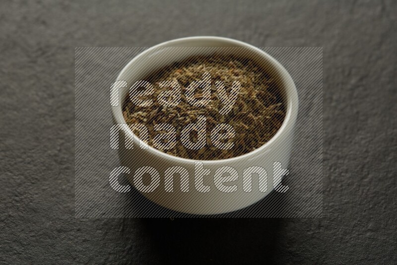 wooden round sauce bowl filled with herbs on grey textured countertop