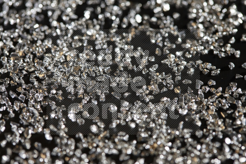 Silver shimmering fragments of glass scattered on a black background