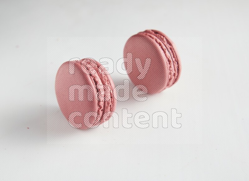 45º Shot of two Pink Raspberry macarons on white background