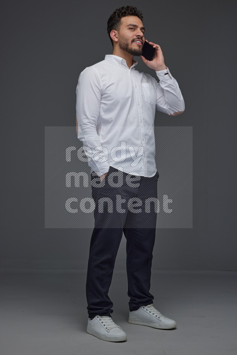 A man wearing smart casual talking in the phone eye level on a gray background