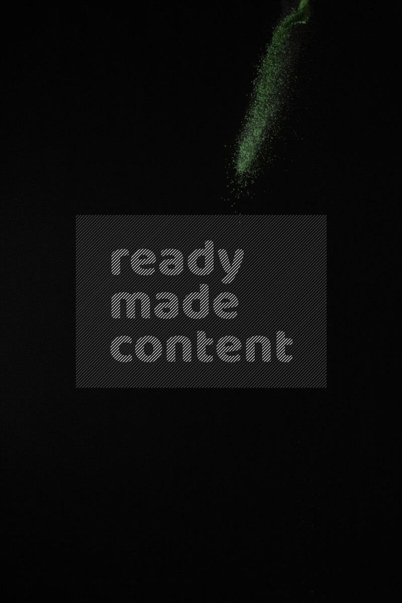 A side view of green powder explosion on black background