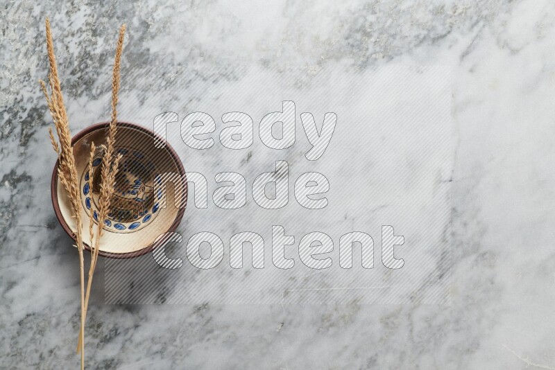 Wheat stalks on decorative pottery plate on grey marble background