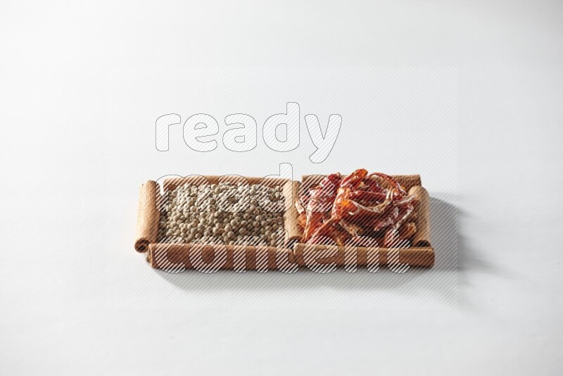 2 squares of cinnamon sticks full of red dried chilis and white pepper on white flooring