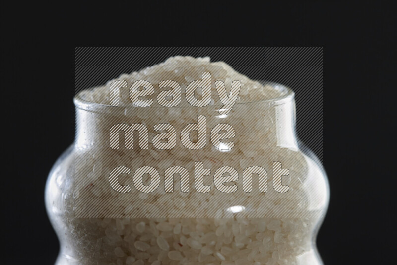 White rice in a glass jar on black background
