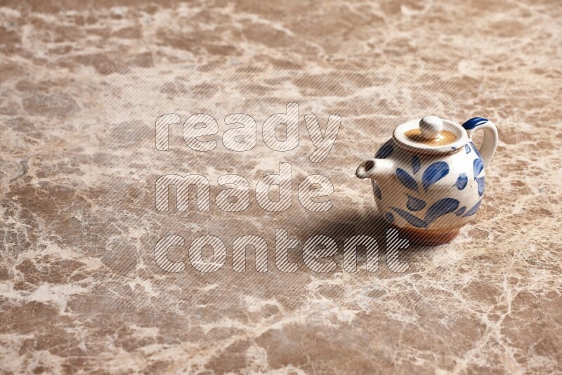 A pottery teapot on beige marble background