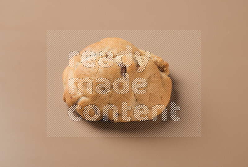 a whole chocolate chip cookie on a brown background