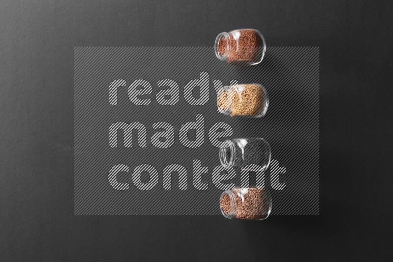 حبة البركة و حبوب الخردل وحبوب الكتان وحب الرشاد في أوعية زجاجية علي خلفية سوداء