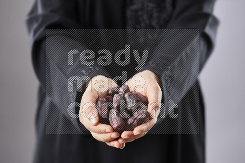 Woman in abaya holding dates in different positions