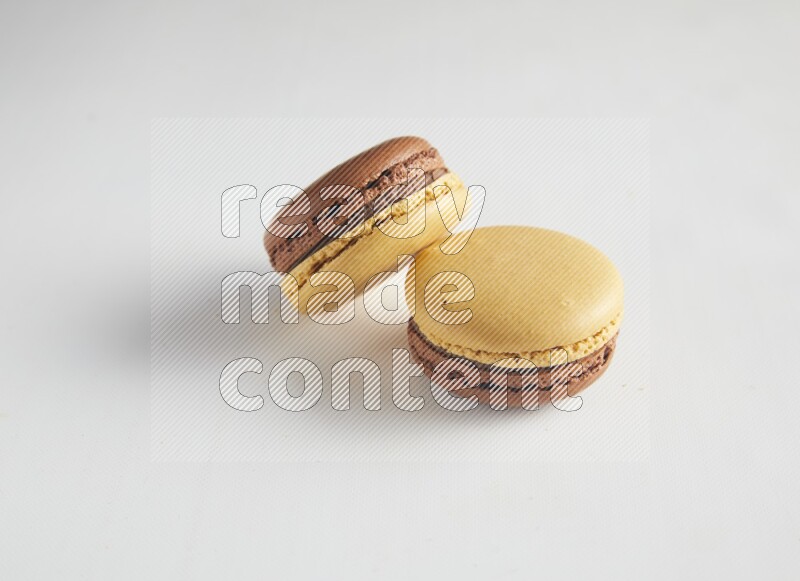 45º Shot of two Yellow and Brown Chai Latte macarons on white background
