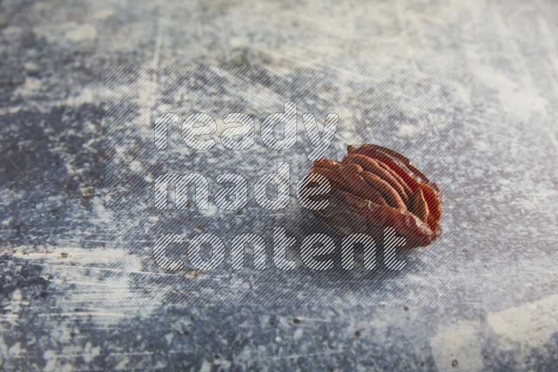 pecan stuffed madjoul date on a rustic blue background