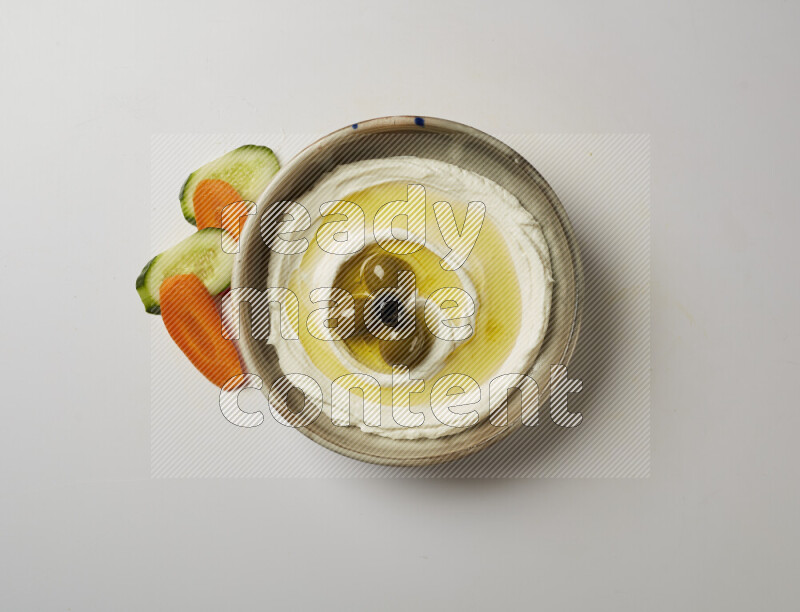 Lebnah garnished with whole olives in a grey pottery plate on a white background