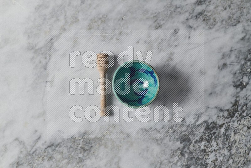 Decorative pottery bowl with wooden honey dipper on the side on grey marble background