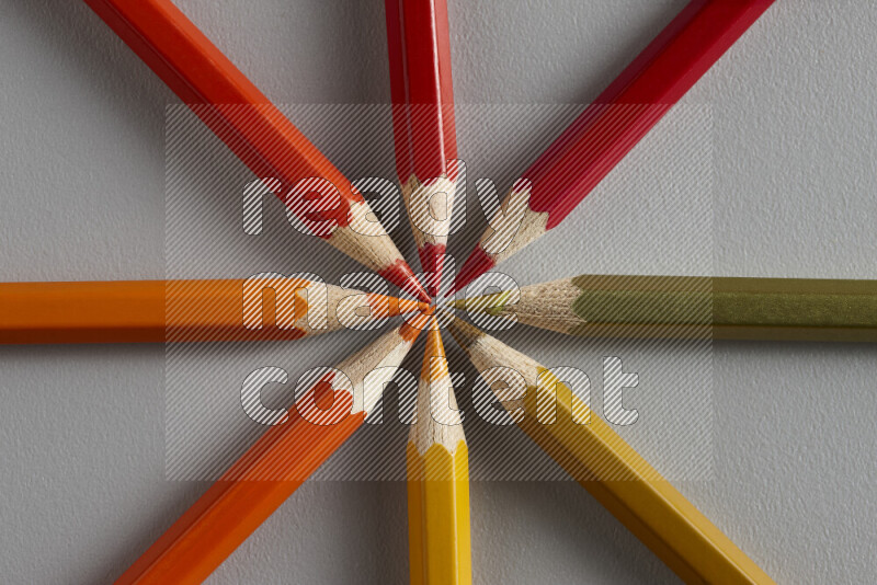 An arrangement of colored pencils in different colors on grey background