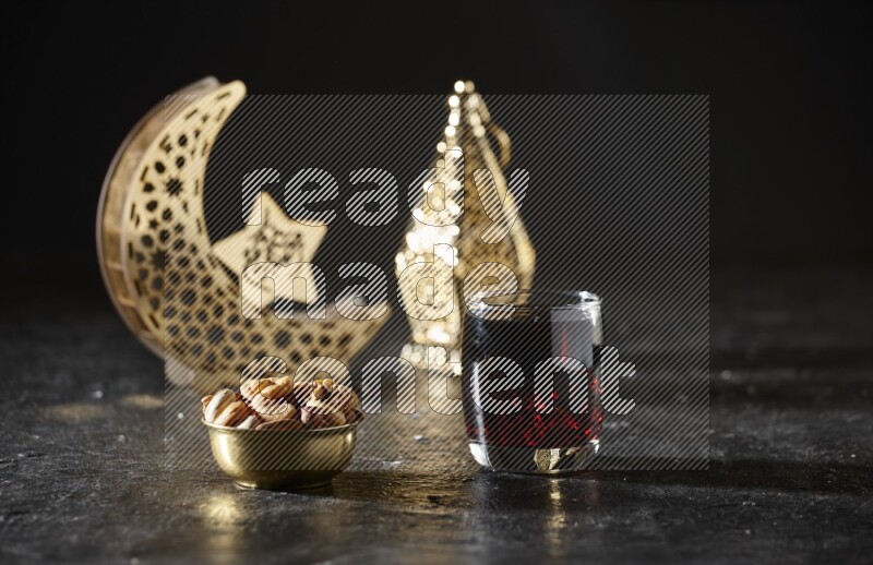 مكسرات في وعاء معدني مع مشروب التمر الهندي بجانب فوانيس ذهبية علي خلفية سوداء