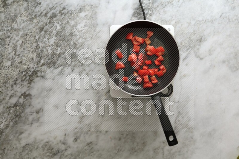 Frying pan on single electric stove on grey marble background