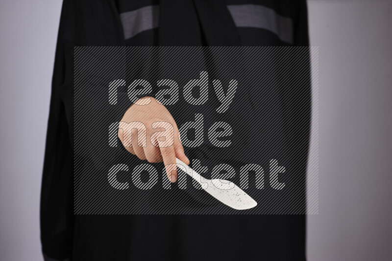 A woman in black abaya holding different wooden essentials in different positions