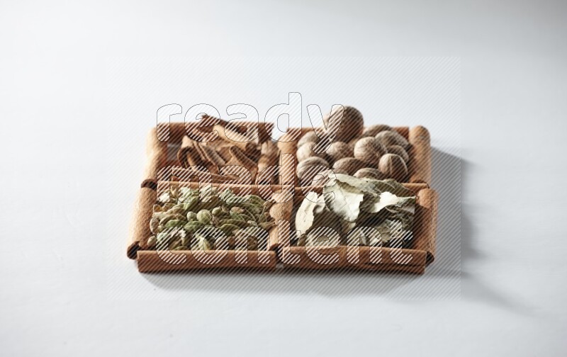 4 squares of cinnamon sticks full of nutmegs, bay laurel leaves, cardamom and cinnamon on white flooring
