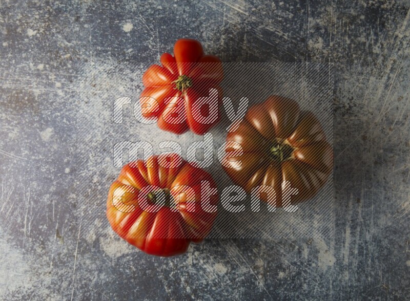 three heirloom tomatoes topview on a textured vinyl background
