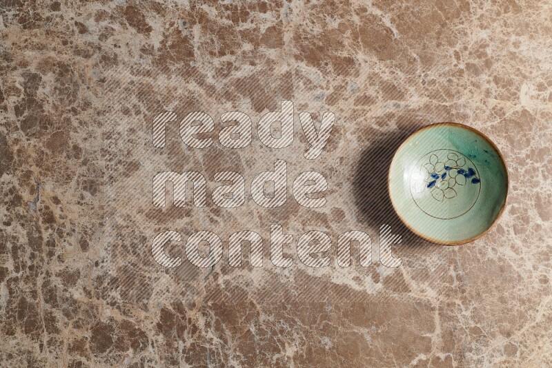 A decorative pottery plate on beige marble background
