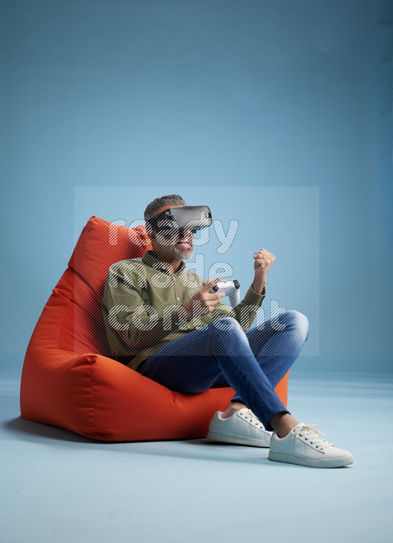A man sitting on an orange beanbag and gaming with VR