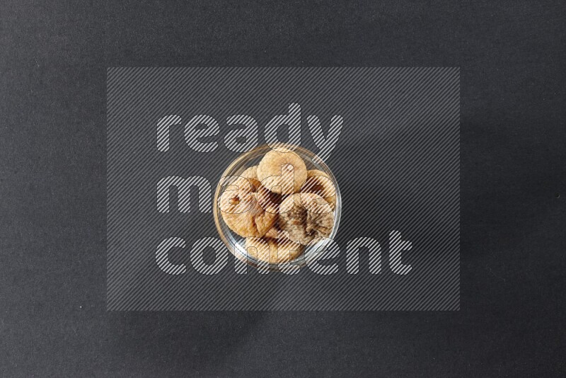 A glass bowl full of dried figs on a black background in different angles