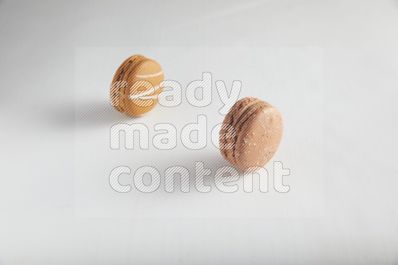 45º Shot of of two assorted Brown Irish Cream, and Brown Hazelnuts macarons on white background