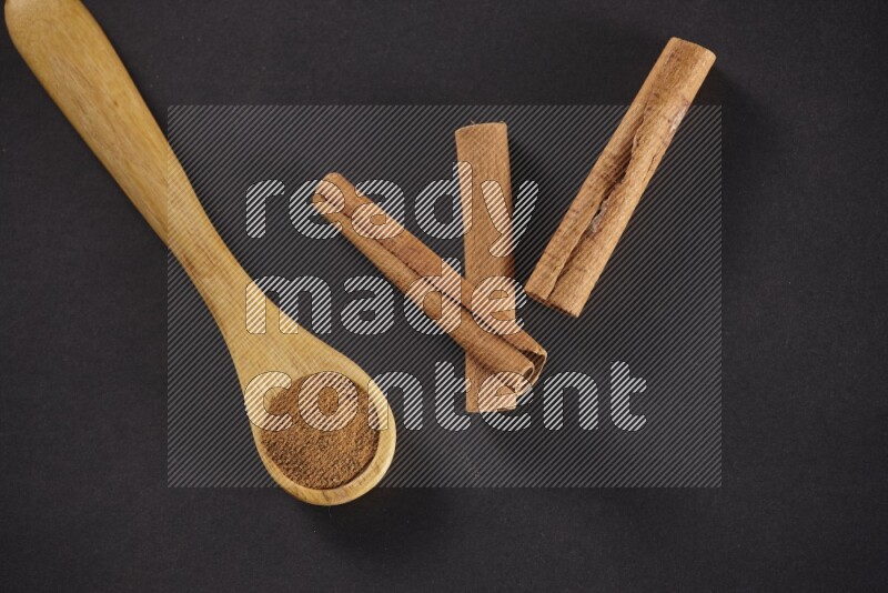 3 Cinnamon sticks stacked beside a wooden spoon full of cinnamon powder on black background in different angles