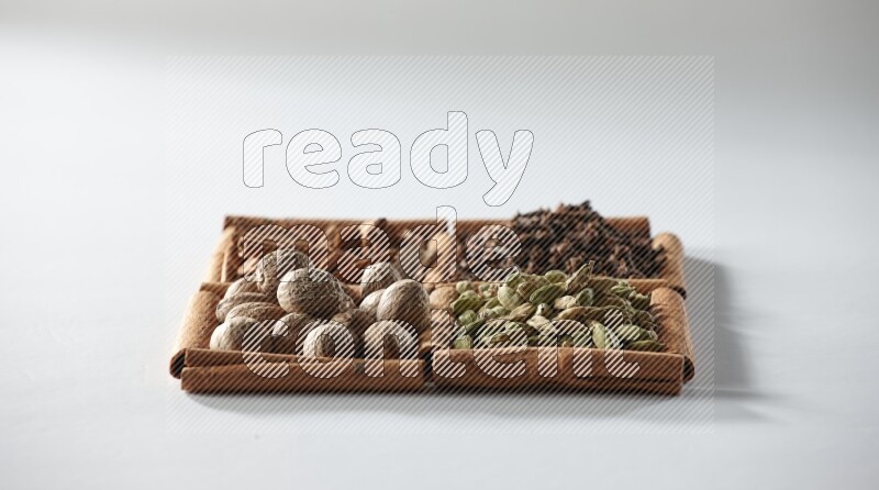 4 squares of cinnamon sticks full of cardamom, cinnamon, cloves and nutmeg on white flooring