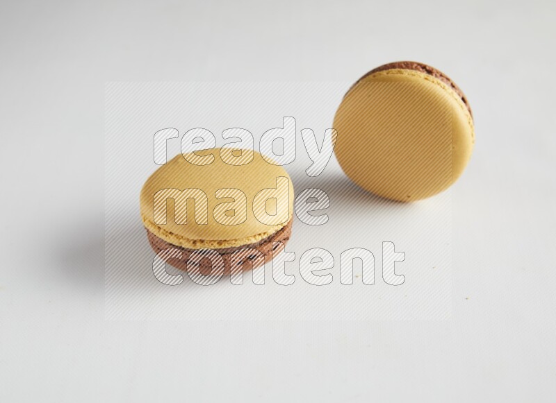 45º Shot of two Yellow and Brown Chai Latte macarons on white background