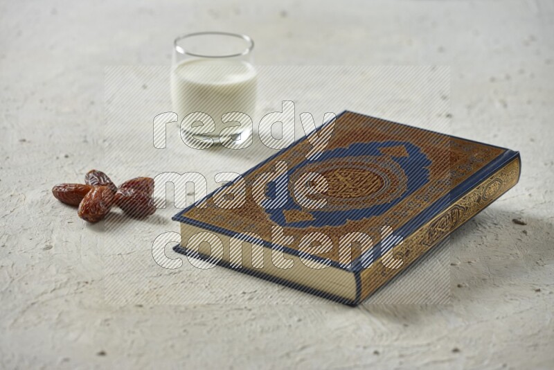 Quran with dates, prayer beads and different drinks all placed on textured white background