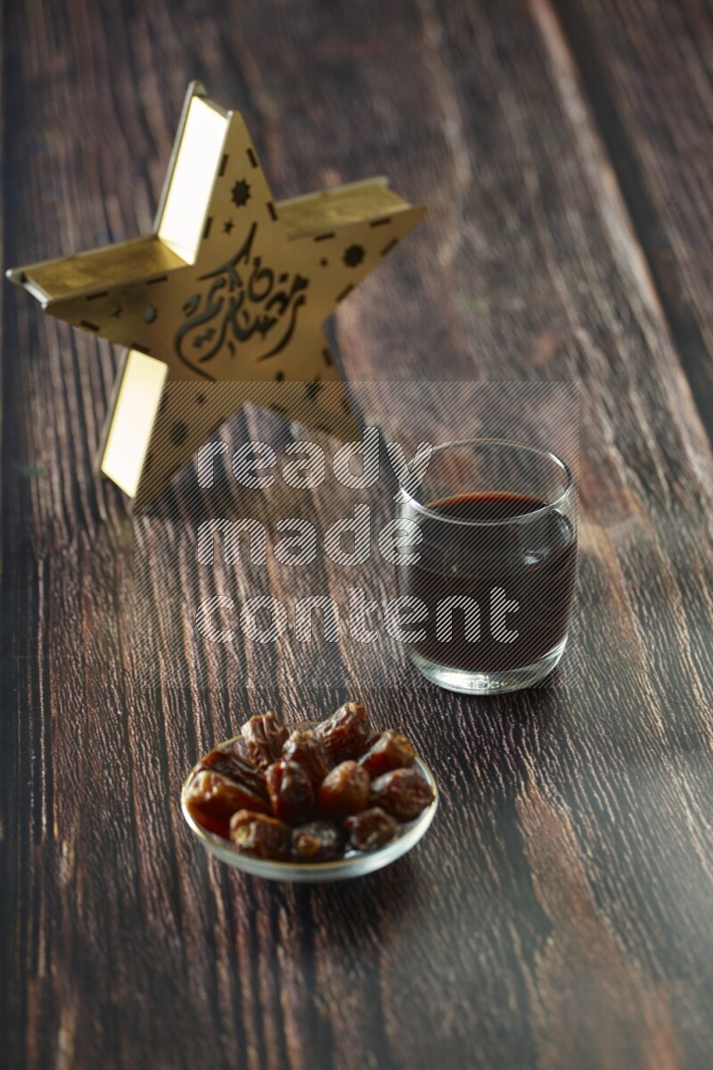 A wooden golden star lantern with different drinks, dates, nuts, prayer beads and quran on brown wooden background