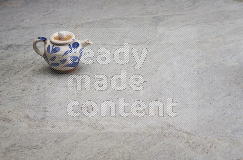 A pottery teapot on grey marble background